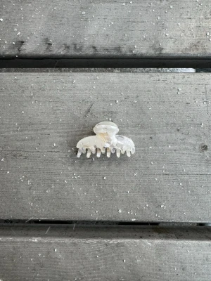 Liten pärlemorskimrande hårklämma - En liten hårklämma i pärlemorskimrande plast med klassisk rundad form och silikon på insidan för bättre greppyta. Perfekt för att snabbt sätta upp håret och ger en stilren touch till din look.🤍