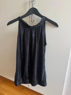 Svart topp med knyte bak  - Svart topp, passar bra till fest, använt någon gång. Står ej storlek men skulle säga att det är en M