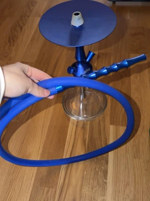 Blå vattenpipa med kolvärmare - Säljer en stilren blå vattenpipa från Aladin med matchande slang och genomskinlig glaskropp. Medföljer även en elektrisk kolvärmare och tång för enkel hantering av kol. Ingen frakt bara mötas upp i STOCKHOLM 