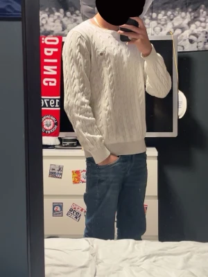 Vit kabelstickad tröja från GANT - Säljer en klassisk vit kabelstickad tröja från GANT i premium bomull. Tröjan har rund halsringning, ribbade muddar och lång ärm. Perfekt för dig som gillar en clean och tidlös stil. Hör av er om ni har några frågor!