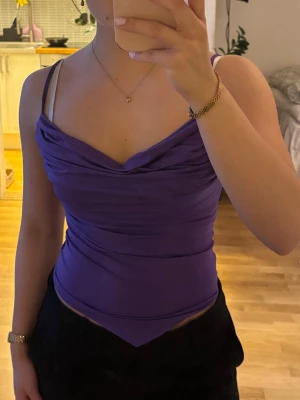 Topp från BikBok, XS - Lila topp från BikBok med draperad urringning och smala axelband. Toppen är figurnära och har en mjuk, stretchig känsla. Har inga tecken på slitage.