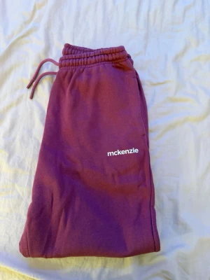 Lila mjukisbyxor från McKenzie - Säljer ett par lila mjukisbyxor från McKenzie med resår i midjan och benslut samt snörning i midjan. Byxorna har en relaxed passform och är gjorda i mjukt bomullsmaterial. Perfekta för chill dagar eller när du vill vara extra bekväm.