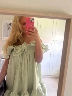 Ljusgrön volangklänning offshoulder - Supersöt ljusgrön kortklänning med volanger och offshoulder-modell. Klänningen har en luftig passform och är perfekt för varma dagar. Tillverkad i ett lätt och mjukt material som känns skönt mot huden.