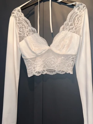 Vit spetsig topp med lång ärm - Superfin topp med öppen rygg och knytband i nacken. 