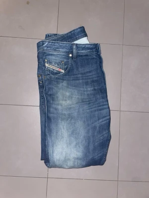 Diesel jeans  - Säljer ett par blå diesel jeans med snygga tvättade detaljer. Klassisk femficksmodell med raka ben och normal passform. Jeansen har diesel-logga på myntfickan och är tillverkade i slitstarkt bomullsmaterial. W33 L34