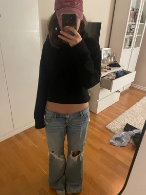 Ljusblå baggy jeans med slitningar - Säljer ett par ljusblå baggy jeans med slitna detaljer och stora hål på båda knäna. Jeansen har låg midja och raka ben, perfekt för en avslappnad och trendig look. Klassisk femficksmodell i jeansmaterial. Använt 2-3 gånger. 