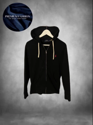 Ralph Lauren zip - Svart hoodie med dragkedja från Polo Ralph Lauren. Klassisk design med vit dragsko i huvan och röd broderad logga på bröstet. Tillverkad i mjukt bomullsmaterial och har två fickor framtill. Perfekt för en avslappnad och stilren look. Perfekt om du vill ha den snyggaste hoodien i klassen! Storlek xs kanske kan passa S🤩Skick 9/10 se bilderna🤗 har du någon övrig fråga eller fundering är det bara att höra av sig!😁mvh premium fashion 