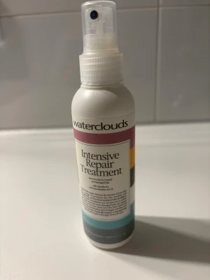 Waterclouds Intensive Repair Treatment - Intensiv hårbehandling från Waterclouds i sprayflaska. Produkten är framtagen för att reparera och vårda skadat hår och innehåller bland annat solrosolja. Flaskan är vit med färgade detaljer och har en praktisk sprayfunktion.