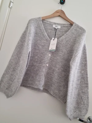 Ljusgrå stickad kofta från Gina Tricot - OBS Jag kan även fixa fri frakt, kontakta mig innan köp 🌸🌸🌸Supermjuk ljusgrå kofta från Gina Tricot i ullblandning. Storlek XS. Koftan har v-ringning, tre knappar framtill och ballongärmar för en chill vibe. Perfekt att slänga över en topp när det är kyligt ute. Ny med prislapp