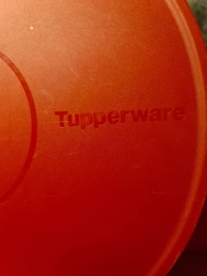 Röda Tupperware burkar med lock - Tre röda plastburkar från Tupperware med tillhörande lock. Perfekta för att förvara mat eller snacks i köket. Burkarna är runda och har olika storlekar, alla med matchande röda lock.