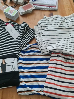 Randiga t-shirts i olika färger - Flera randiga t-shirts i olika färger och mönster. Här finns svartvita, blåvita, röda och beige ränder. Klassisk passform och rund halsringning, perfekt för en avslappnad stil. Några har tryckdetaljer och alla är kortärmade.