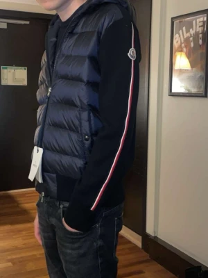 Mörkblå cardigan från Moncler - Snygg mörkblå cardiganfrån Moncler med klassisk quiltad design och Moncler-logga på bröstet. look. Köpt i sthlm för 12k på nk kvitto box finns.