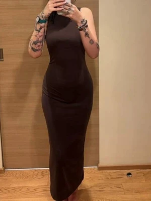 Mörkbrun långklänning Shein - Säljer en stilren mörkbrun långklänning med hög hals och ärmlös design. Klänningen har en figurnära passform och är tillverkad i ett mjukt, stretchigt material som ger en snygg siluett. Perfekt för dig som gillar minimalistisk och elegant stil. Priset kan diskuteras och skicka meddelande för mer info 🤍
