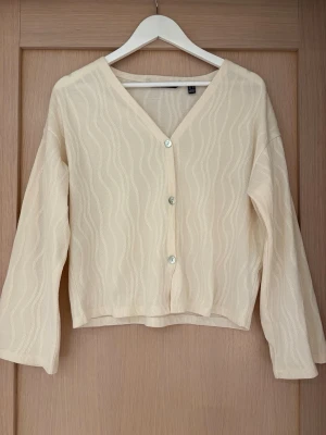 Krämvit kofta med vågigt mönster - Säljer denna kofta från Vero Moda i storlek XS. Den är använd fåtal gånger så väldigt bra skick🤗