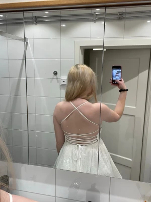 Vit glittrig studentklänning  - Glittrig klänning med dragkedja och knytning i ryggen. Använd en gång.