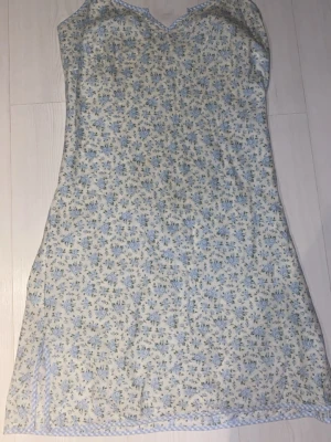 Coquette Blommig sommarklänning - Söt klänning från vintage Laura Ashley med ljusblått blommönster på vit botten. Klänningen har smala axelband. Perfekt för varma dagar och har en lätt, luftig känsla.