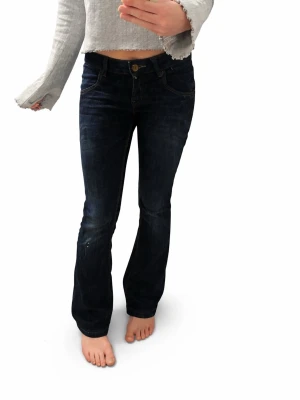 Mörkblå bootcut jeans EUR 34 - Snygga mörkblå bootcut jeans med klassisk femficksmodell och regular fit. Jeansen har gul kontrastsöm och knappgylf. Perfekta till en avslappnad och trendig look. Jag är 160cm!