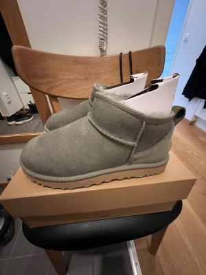 UGG Classic Ultra Mini - UGG Classic Ultra Mini i färgen grön. De är dock mer grå i verkligheten, som man också ser på bilderna. Helt oanvända, endast provade☺️ I storlek 39. 