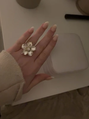 Stor blomformad ring i silverfärg - Statementring i form av en stor blomma med diamant i mitten från Ioaku! Ringen är justerbar