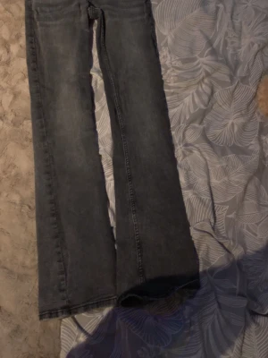 Bootcut jeans från H&M, grå - Snygga grå bootcut jeans från H&M med justerbar midja och låg midja. Klassisk femficksmodell i mjuk bomullsdenim med en lätt utsvängd passform nedtill. Perfekta för dig som gillar en avslappnad men trendig look.