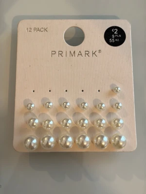 Pärlörhängen i olika storlekar Primark - Set med 12 par klassiska pärlörhängen från Primark i olika storlekar. Örhängena är vita och har en rund form med glansig yta, tillverkade i syntetmaterial. Perfekta för att mixa och matcha till olika looks.