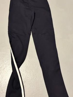 Mörkblåa leggings med vit sidoremsa Cubus - Blå svarta leggings med en vit rand längs utsidan av benen. Stretchigt material som sitter tight och ger en sportig vibe. 