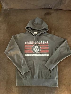 Saint Laurent hoodie - Säljer en saint Laurent hoodie i bra skick, det finns inga slitage eller skador. Hör av dig vid fler funderingar. På hoodien står det storlek M men den är som en S. 