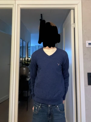Blå stickad tröja från GANT - Säljer för 450 den är bra kvalitet och  perfekt för dig som gillar stickade kläder storlek 11-12 146-152. mysig blå stickad tröja från GANT med v-ringning och diskret logga på bröstet. Tröjan har långa ärmar och ribbade muddar vid ärmslut och nederkant. Perfekt för dig som gillar klassisk och enkel stil.