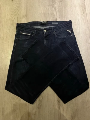 Mörkblå Replay Anbass jeans - Snygga mörkblå jeans från Replay med raka ben och klassisk femficksdesign. Jeansen har diskreta kontrastsömmar och en svart Replay-lapp bak i midjan. Tillverkade i slitstarkt denimtyg som ger en tidlös look. Storlek W31 L34