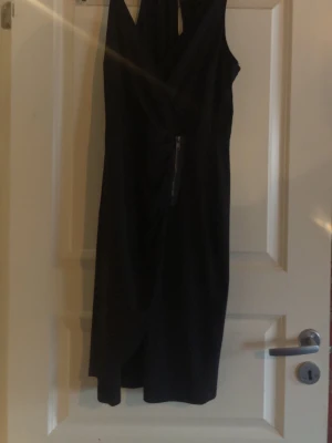 Svart omlottklänning från TrulyMine - Snygg svart omlottklänning från TrulyMine i storlek 36/38. Klänningen har en omlottdesign med markerad midja och dragkedjedetalj framtill. Perfekt för dig som gillar stilrena och trendiga plagg.