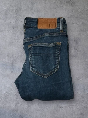 Tiger of Sweden Jeans - Snygga blå jeans från Tiger of Sweden med klassisk femficksdesign och en brun skinnpatch i midjan. Jeansen har raka ben och diskreta slitningar för en avslappnad look. Perfekta till vardagsstilen och passar till det mesta.