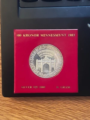 100 kronor minnesmynt 1983 silver 16gram - Säljer ett svenskt minnesmynt på 100 kronor från 1983 i silver (925/1000), vikt 16 gram. Myntet har motiv av Sveriges riksdag och Helgeandsholmen och kommer i en röd fyrkantig förpackning med guldfärgad text.