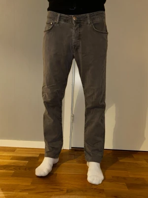 Grå jeans från Jacob Cohen - Snygga grå jeans från Jacob Cohen med klassisk femficksdesign och raka ben. Jeansen har normal passform och är tillverkade i mjukt bomullsmaterial med en diskret logga på bakfickan. Perfekta för en stilren och avslappnad look. 32/32