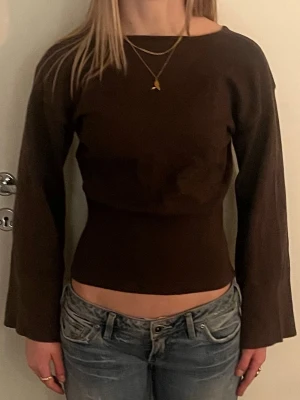 Brun långärmad croppad topp - Mörkbrun långärmad topp med croppad passform och lätt utsvängda ärmar. Sitter tight över midjan och har en enkel, stilren design utan mönster eller detaljer. Perfekt att styla med jeans eller kjol. Pris kan diskuteras! 🫰🏻🩷