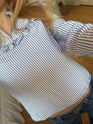 Randig blus - Snygg blus med blå och vita smala ränder och volang längs bröstet och axlarna. Storlek 34/xs från Zoul💕