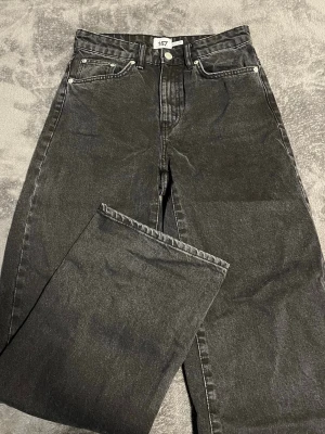 Svarta raka jeans från 157 - Snygga svarta jeans från 157 med rak passform och klassisk femficksdesign. Jeansen har hög midja och är tillverkade i ett robust denimtyg som ger en tidlös look. Perfekta att matcha med en hoodie eller t-shirt för en chill stil. Den är lite liten i storleken, finns fickor på baksidan.