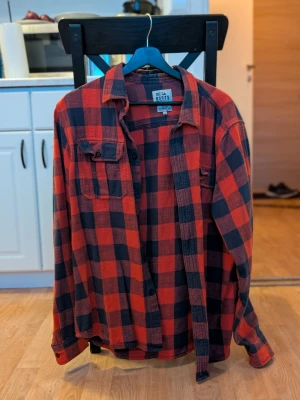 Rutig flanellskjorta – Roots (Lager 157) – stl L - Säljer en röd/svart rutig flanellskjorta från Roots (Lager 157). Använd några gånger, i fint skick. 🔸 Storlek: L 🔸 Klassisk rutig modell 🔸 Mjuk och bekväm – perfekt till höst/vinter 🔸 Inga hål eller fläckar Pris: 200 kr Kan skickas mot frakt eller hämtas upp enligt överenskommelse. Hör av dig vid intresse!