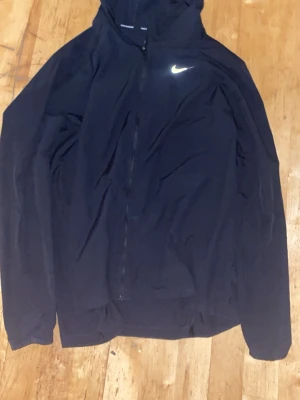 Svart Nike hoodie/flecce  med dragkedja - Säljer en svart hoodie från Nike med dragkedja . Klassisk Nike-logga i vitt på bröstet. Hoodien har långa ärmar och är tillverkad i ett mjukt material som passar perfekt till en sportig eller chill stil.                  Det finns en jätte liten håll