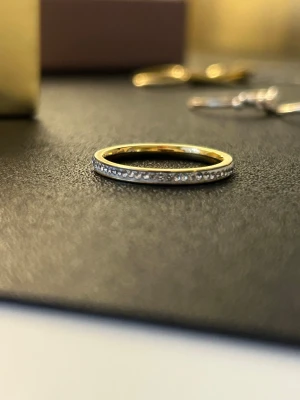 Tunn guldring med små stenar - Elegant tunn ring i guld med en rad små gnistrande stenar runt hela ringen. 