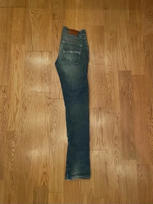 Nudie jeans  - Snygga blå jeans från Nudie jeans med skinny fit. Storleken är 30/34 och nypris är 1600! Det finns slitningar vid fötterna.