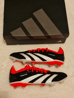 Adidas Predator 24 Pro FG - Adidas Predator 24 Pro FG Black/Solred.  Ny med prislapp   Skick: 10/10 Storlek: 44 Produktkoden: IG7777
