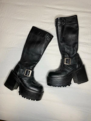 Svarta platåstövlar med spänne - Vintage El Dante’s platform støvletter. Skinnet er i fin tilstand og nylig pleiet med skinnbalsam. Det er noen sprekker i sålen, men det er ikke merkbart og viser ingen antydning til å bli verre. Veldig solide.   london underground sonax buffalo new rock roots destroy john fluevog goth gothic demonia 90s 90-tallet boots støvler hæler høyhælte dantes