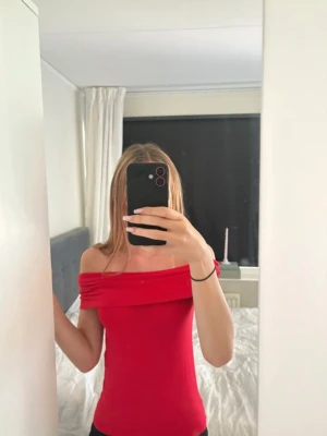 Röd offshoulder tubtopp - Trendig röd tubtopp med offshoulder-design och bred kant upptill. Sitter tight och har en enkel, stilren look som passar perfekt till jeans eller kjol. Materialet känns mjukt och stretchigt, vilket gör toppen bekväm att bära hela dagen.