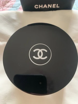 Chanel lös foundationpuder - Lös foundationpuder  i en rund svart burk med klassisk logga. Pudret har en ljus, neutral ton och kommer med en mjuk puff. 