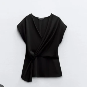 Svart omlottopp med knyt från Zara - Säljer en svart omlottopp från Zara med snygg knytning i midjan och v-ringad. 