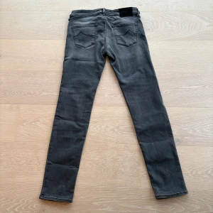 Grå skinny jeans från Jacob Cohën - Snygga grå jeans från Jacob Cohën i skinny fit. Jeansen har klassisk femficksdesign, svarta detaljer och svart patch bak i midjan. Tillverkade i mjukt denimtyg med lätt tvättad look och dragkedja i gylfen. Perfekta för dig som gillar stilrena och moderna jeans.