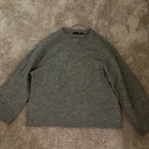 Grå stickad tröja  - Mysig grå stickad tröja från 157 i storlek XS. Tröjan har rund hals och långa ärmar, perfekt för att hålla dig varm under kyliga dagar. Enkel och stilren design som funkar till många olika outfits.