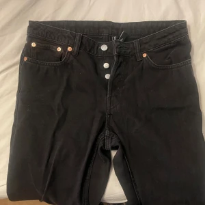 Mörkgråa vida jeans från Weekday W28 L30 - Mörkgråa åjeans från Weekday med klassisk femficksdesign och knappgylf. Jeansen har raka ben och normal passform, tillverkade i bomull. Perfekta för dig som gillar en enkel och stilren look. Lite lägre i midjan, köpt för något år sedan men aldrig använda då dom är för små