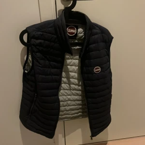  Colmar väst - Snygg dunväst från Colmar med quiltad design och hög krage. Västen har dragkedja framtill och Colmar-logga på bröstet. Perfekt för lager-på-lager och ger en sportig vibe. Mörk blå