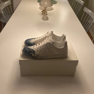 Maison Margiela vita sneakers med blå stänk - Snygga skor i vitt tyg andvänd 2-3 gånger innan .